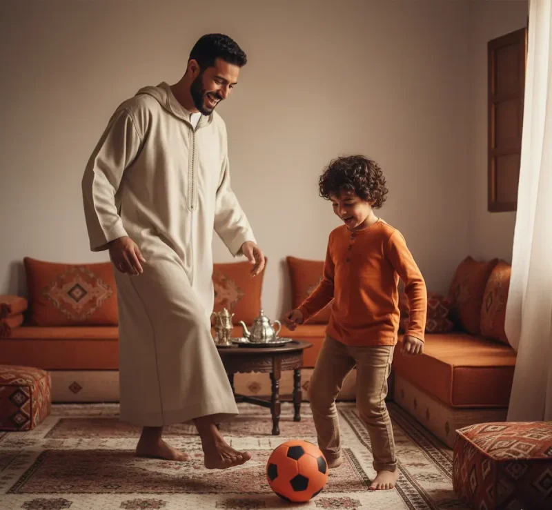 أب مغربي بجلابة يلعب كرة القدم مع ابنه الصغير داخل صالون مغربي تقليدي لتعزيز التواصل