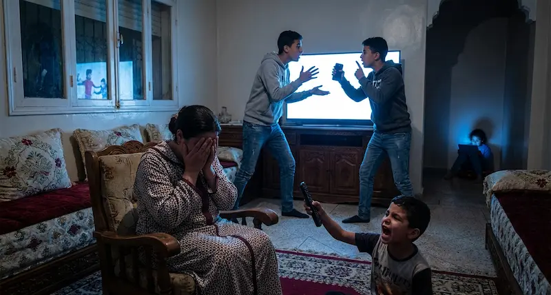 عائلة مغربية تعاني من آثار إدمان الأطفال على الشاشات، طفل غاضب ومراهقين مشتتين.